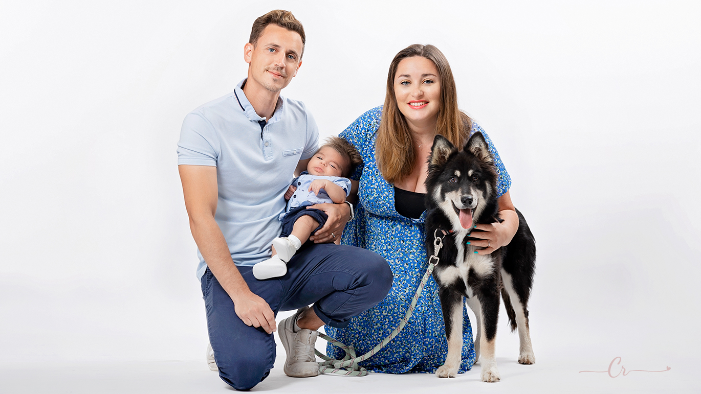 Séance photo au studio de saint-esteve d'une famille avec son nouveau né et son animal de compagnie, un chiot husky. Photo par Carolina Rubio Photography.
