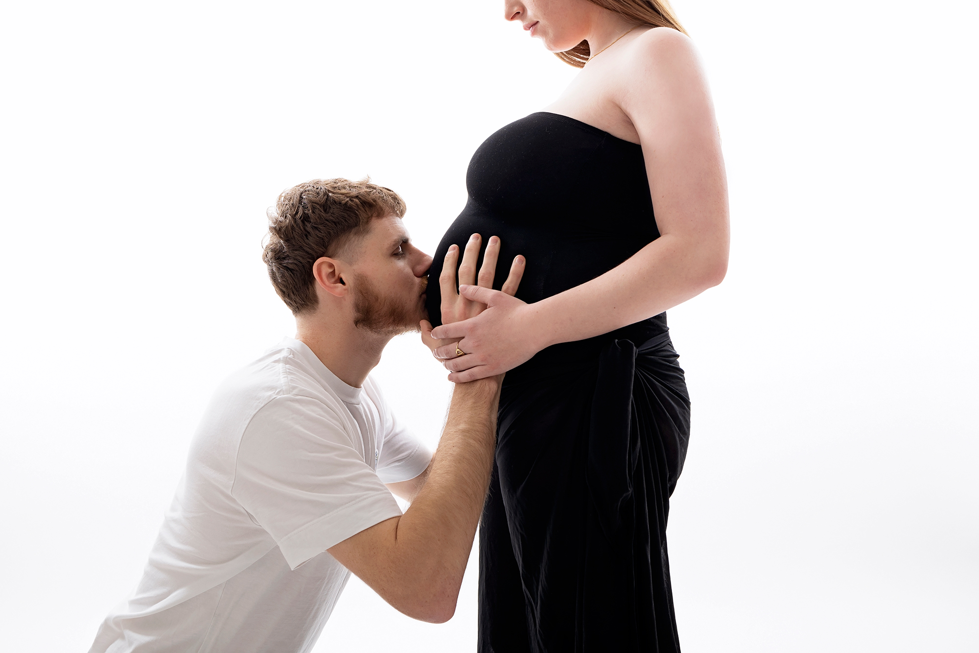 Photo de papa donnant un bisous au centre de sa femme enceinte