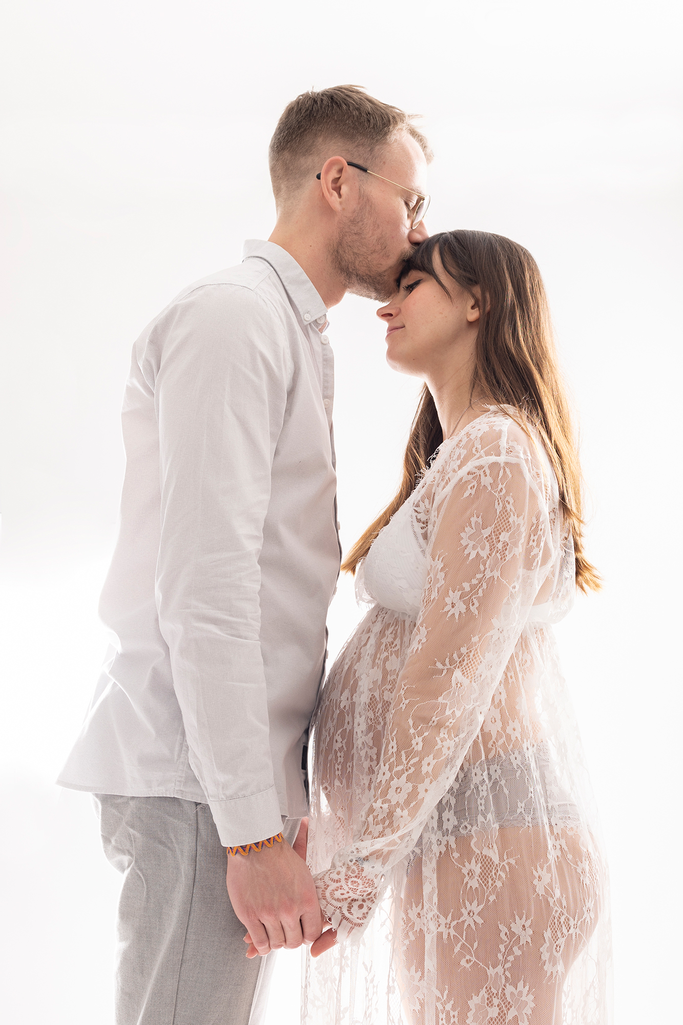 Photographie de séance de grossesse en couple, tenues blanc et fond blanc.