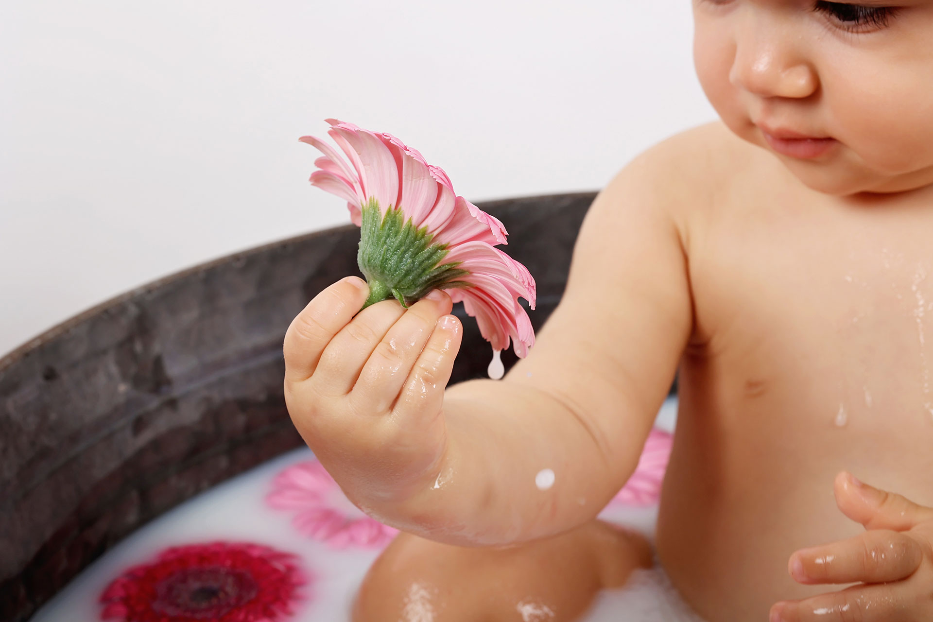 Bébé fille qui profite des fleurs du bain de lait.