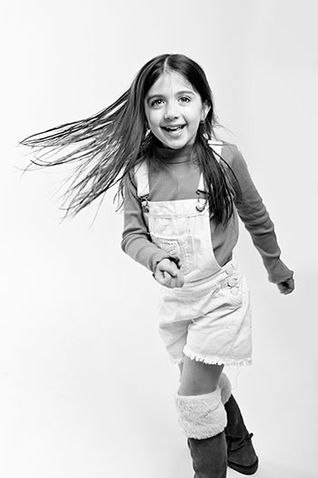 Photo d'une fille de cinq ans en noir et blanc, elle danse et ses cheveux s'envole vers le côté. 