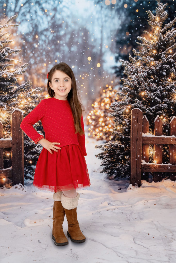 Mini séance de Noël d'une fille de 5 ans habillée en rouge dans un décor festif,, simulant une forêt enneigé  à Pezilla-la-Rivière par Carolina Rubio Photography