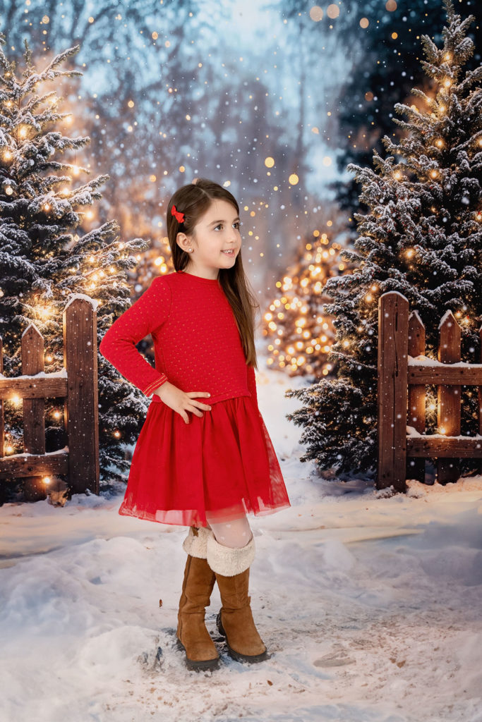 Mini séance de Noël d'une fille de 5 ans habillée en rouge dans un décor festif,, simulant une forêt enneigé  à Pezilla-la-Rivière par Carolina Rubio Photography